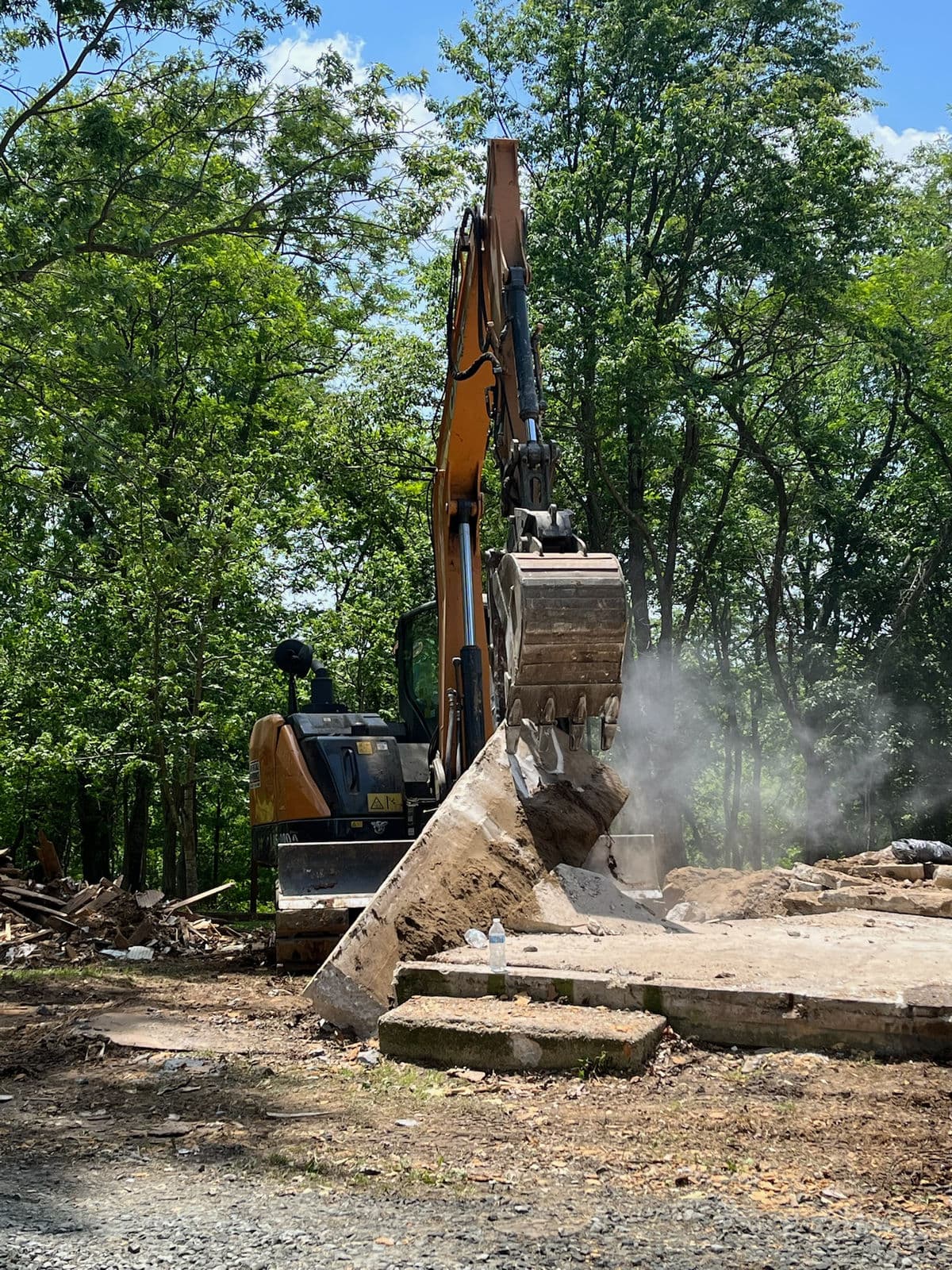 Excavator demolishing a residential structure with debris piled for removal
